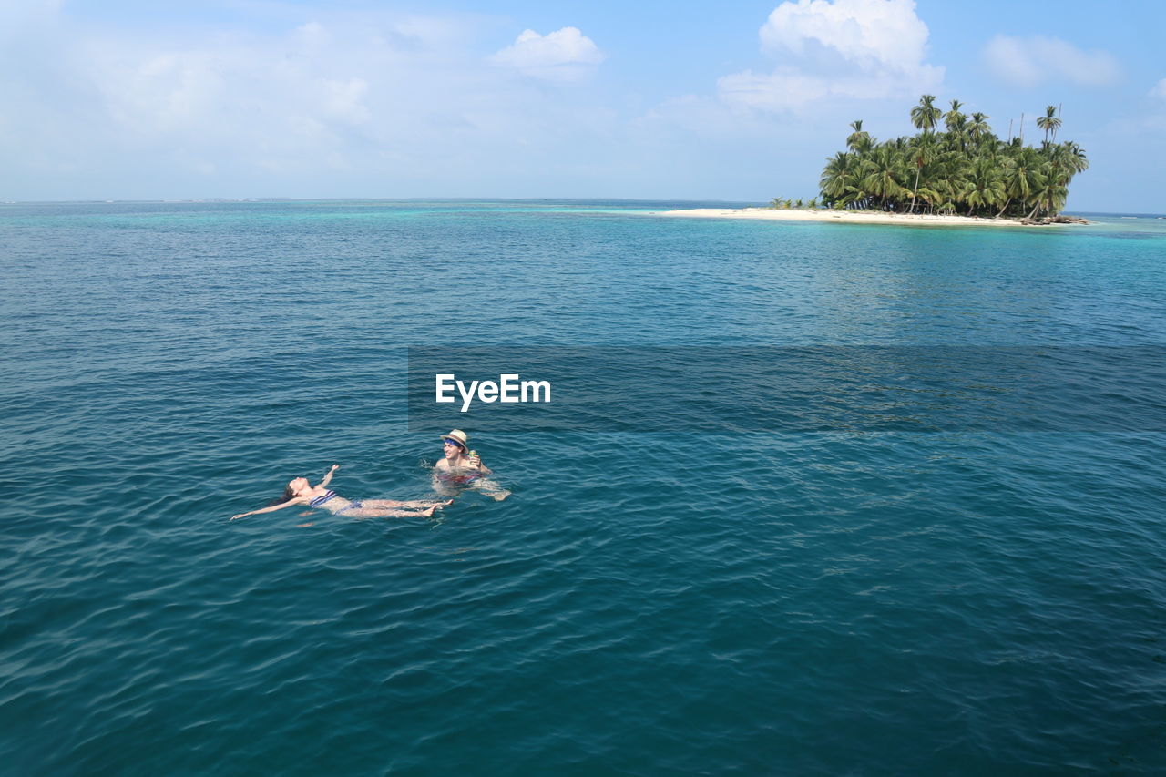 Couple swimming in sea against sky