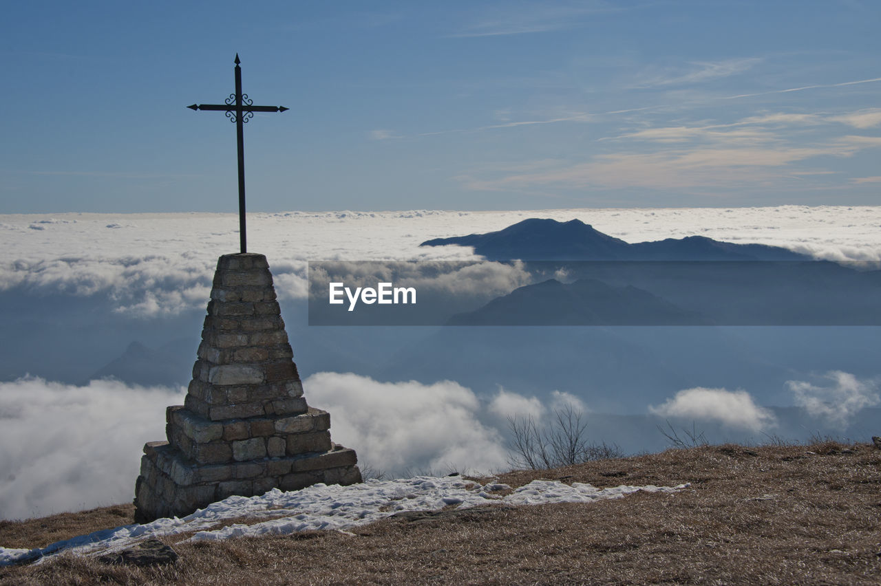 Cross on mountain against cloudscape