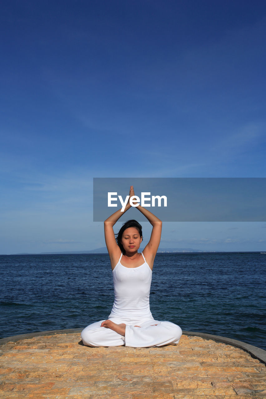 Woman doing yoga against sea and sky