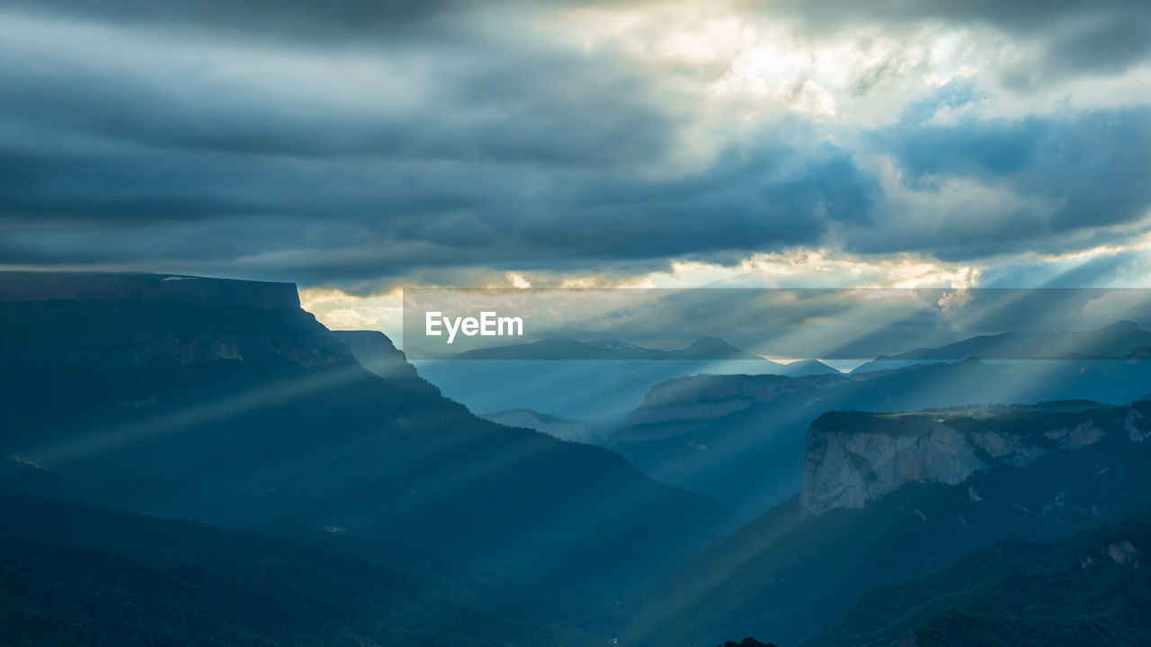 Beautiful mountain landscape. black clouds over a mountain gorge. slanting rays of the setting sun