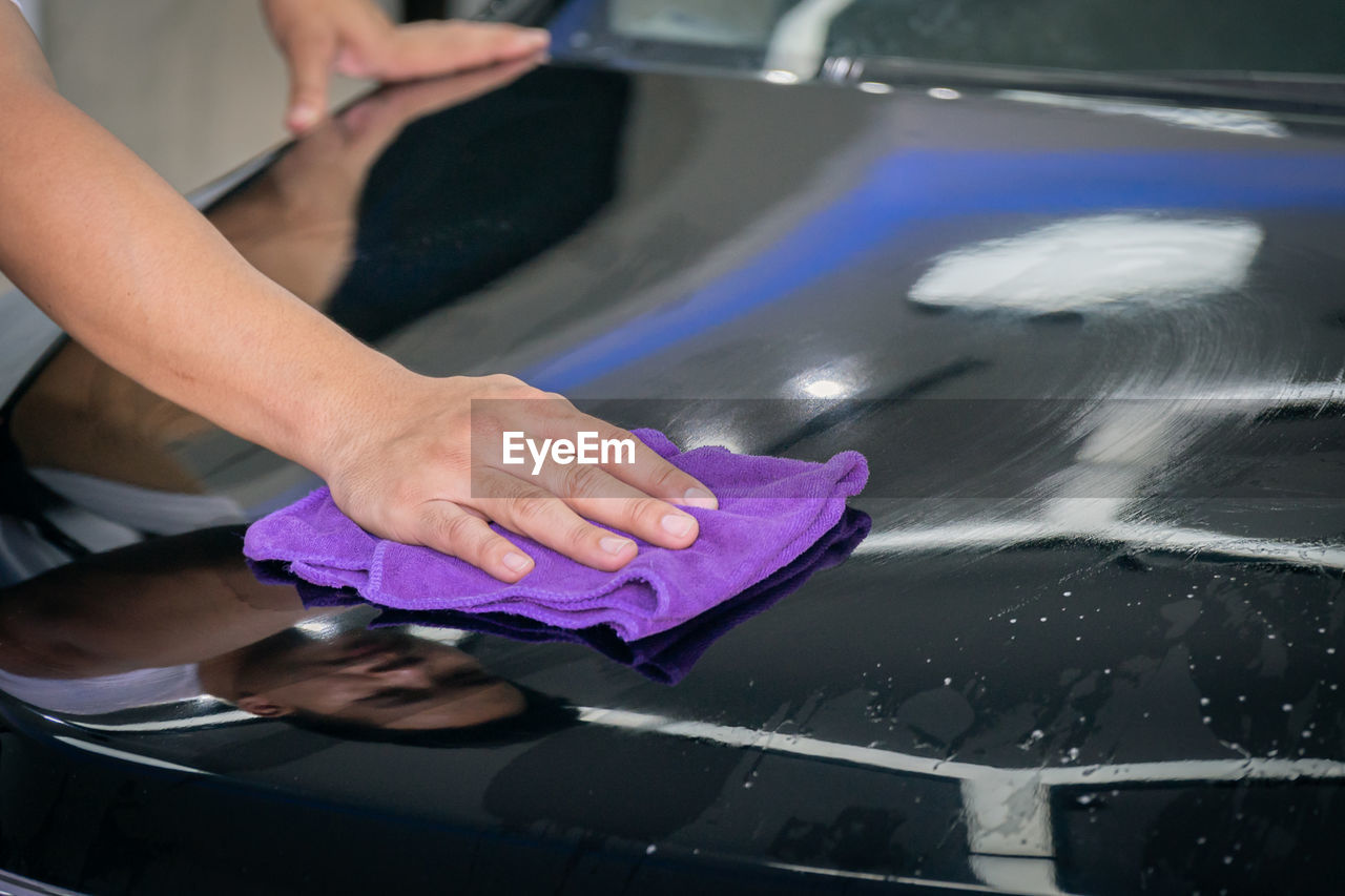 Cropped hand of man cleaning car in garage