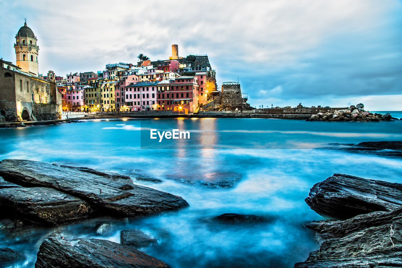 View of illuminated vernazza village reef and sea during at blue hour, five towns, liguria, italy