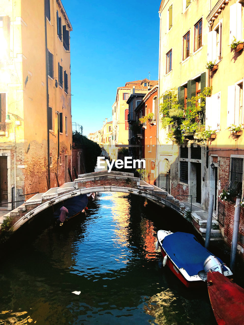 Canal amidst buildings in city against sky