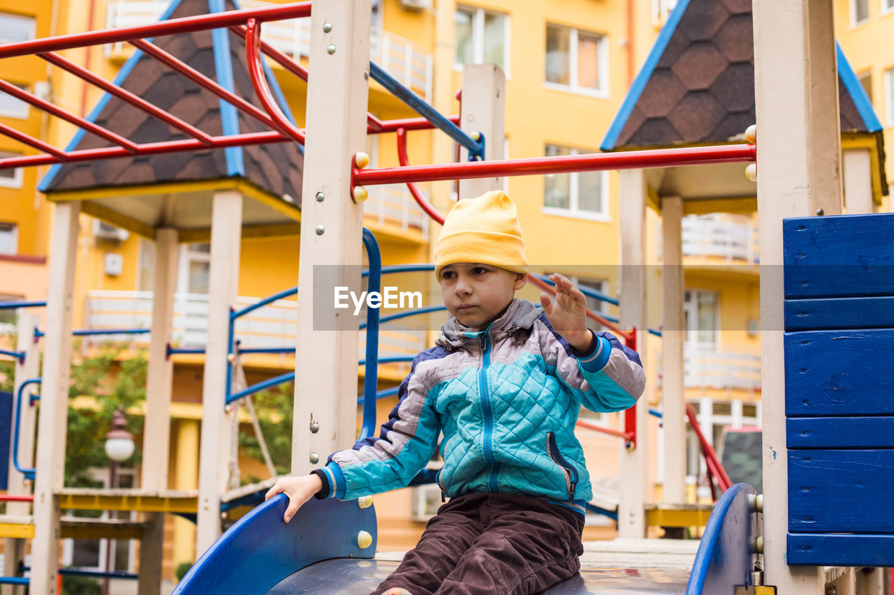 Full length of happy girl standing on slide in playground