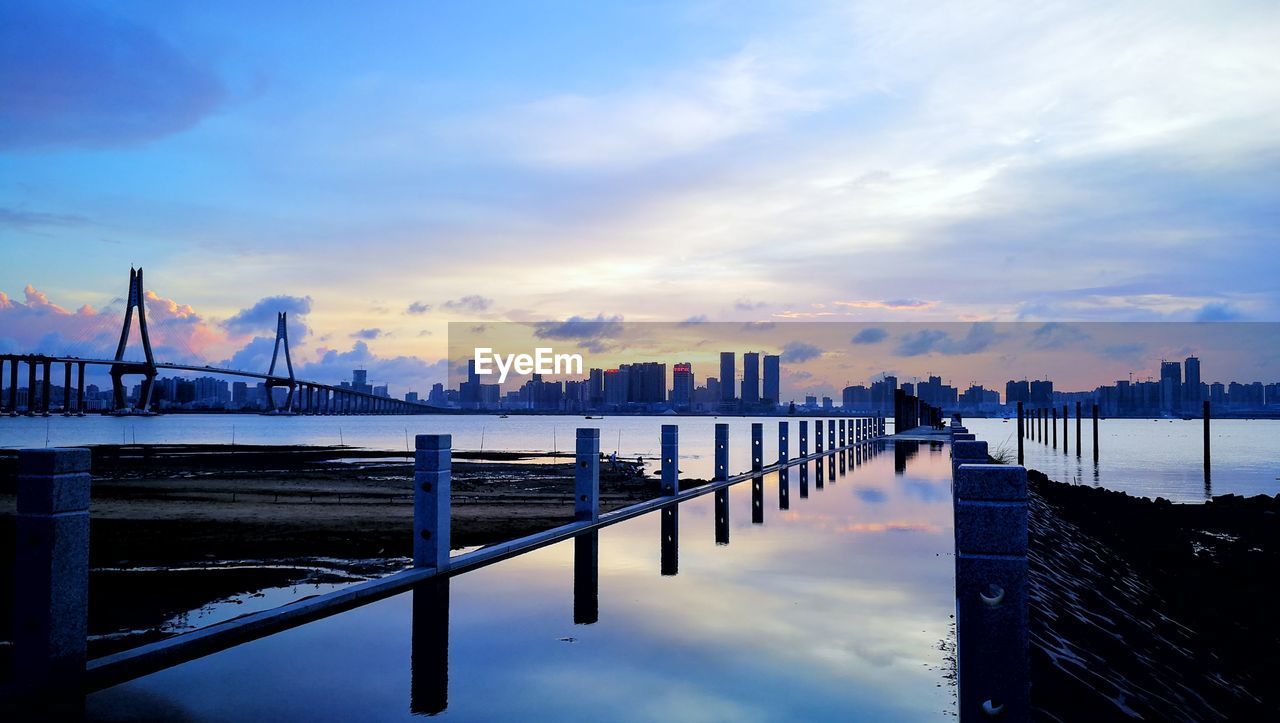 BRIDGE OVER CITY AGAINST CLOUDY SKY