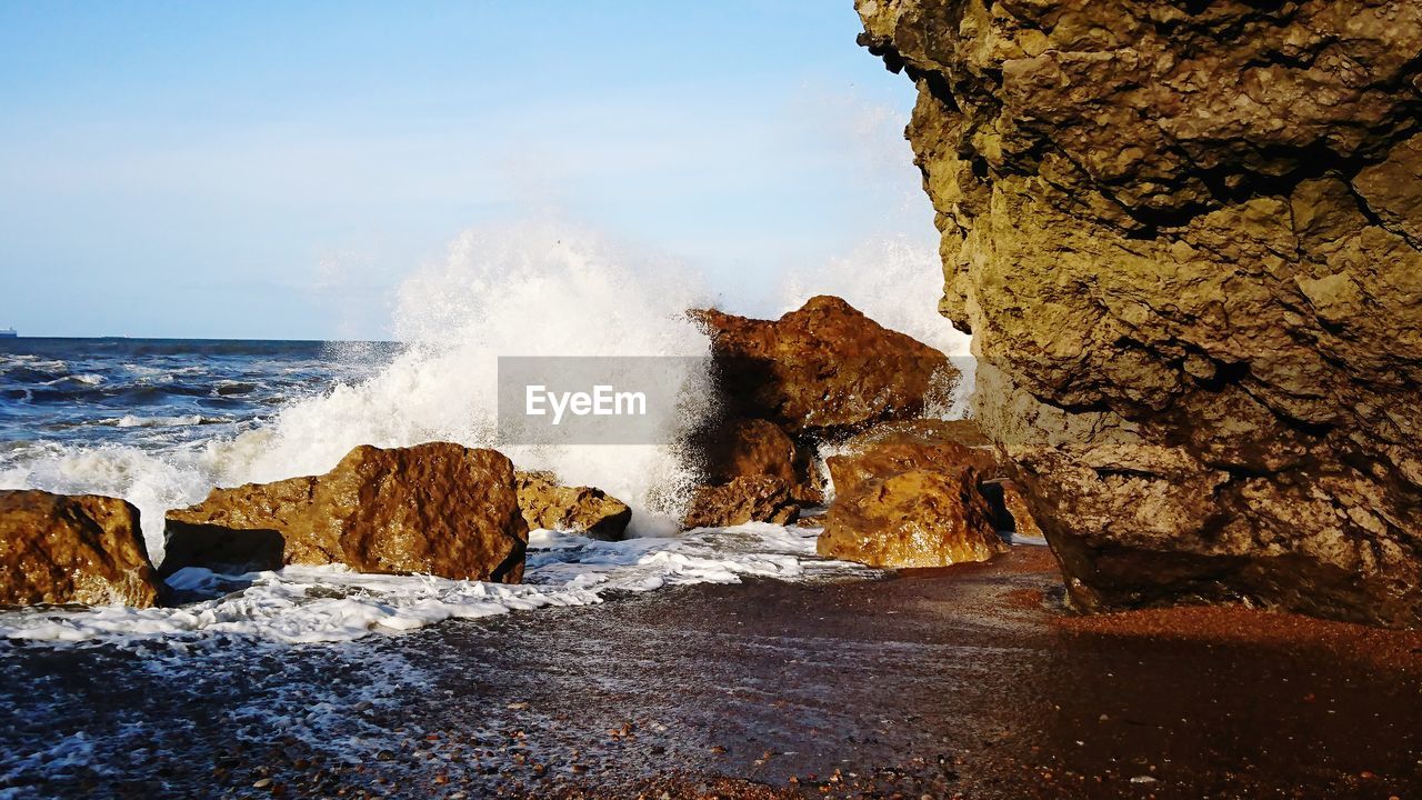 SCENIC VIEW OF SEA WAVES SPLASHING ON ROCK