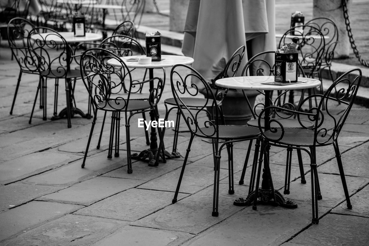 EMPTY CHAIRS AND TABLES AT SIDEWALK CAFE