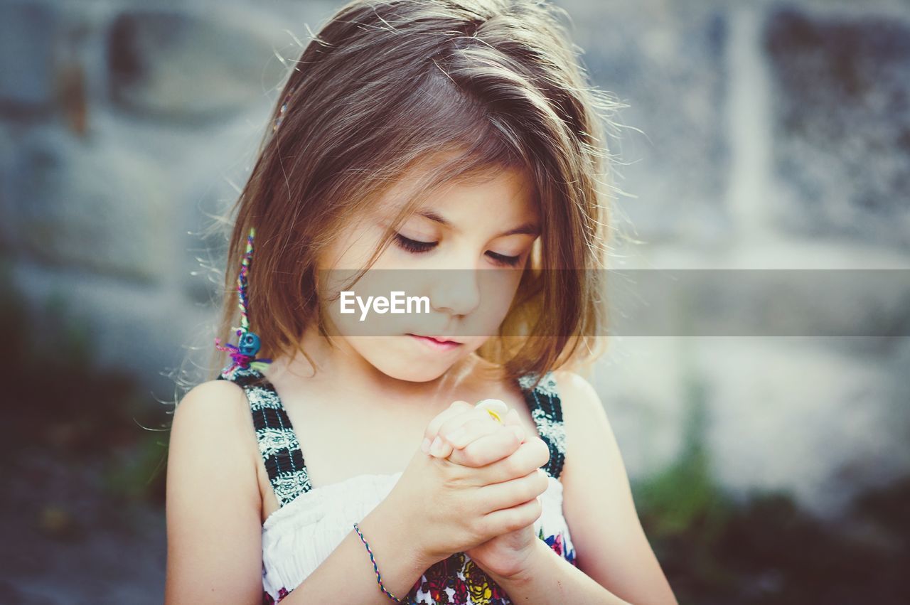 Close-up of cute girl standing with hands clasped