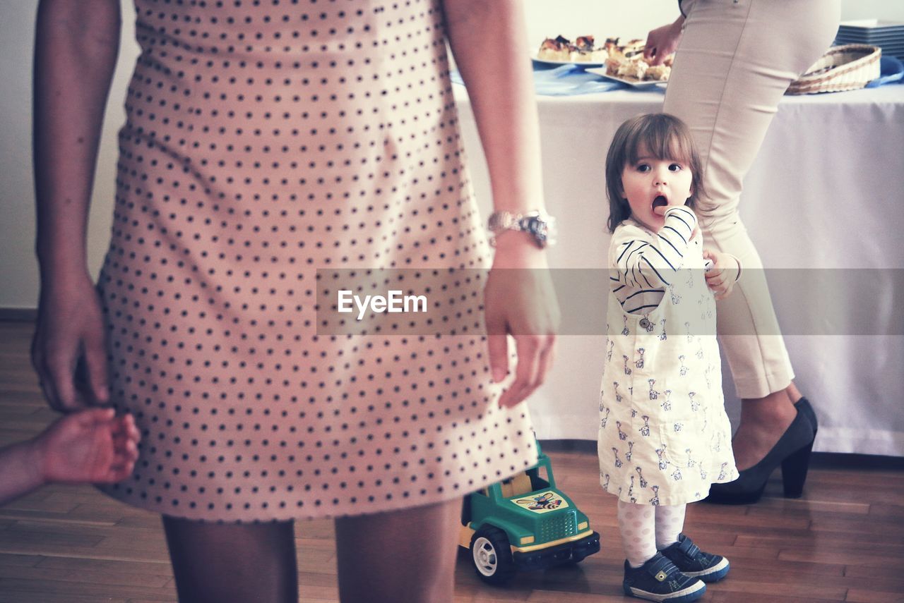 Low angle view of a toddler amongst adults at a party