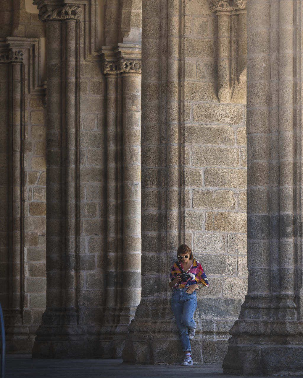 WOMAN STANDING BY BUILDING AT COLONNADE