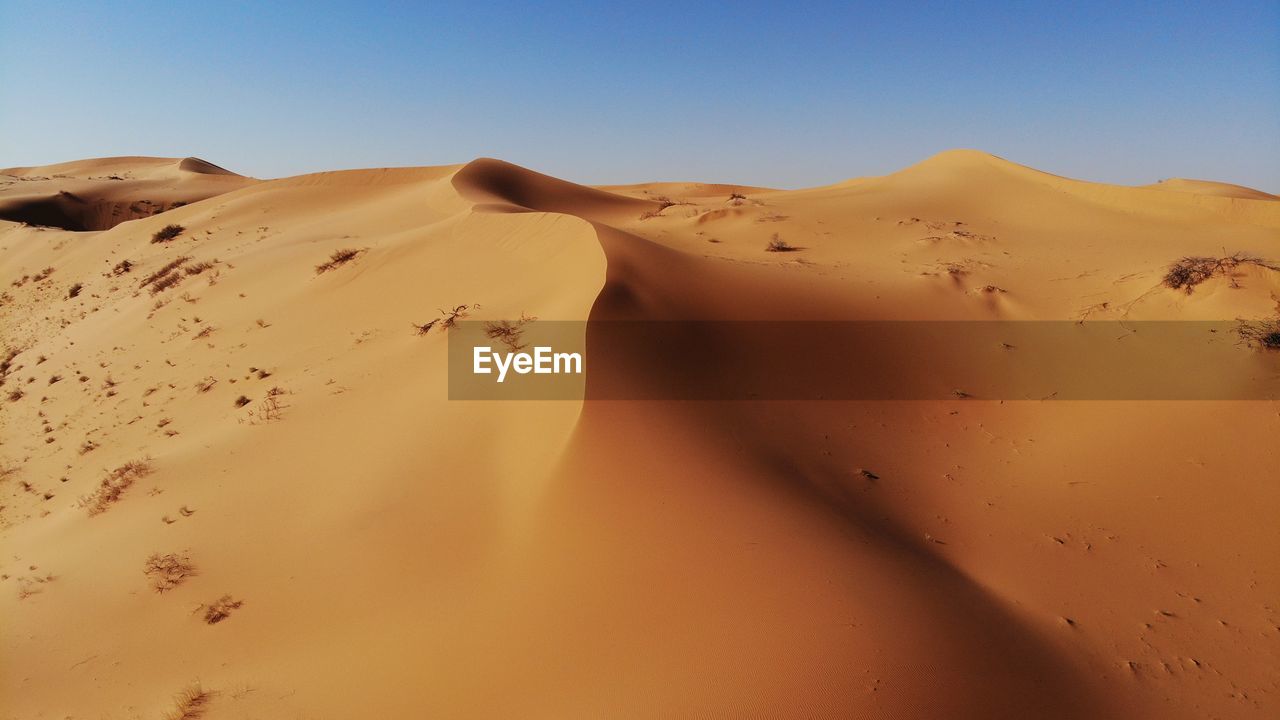 Sand dunes in desert against clear sky