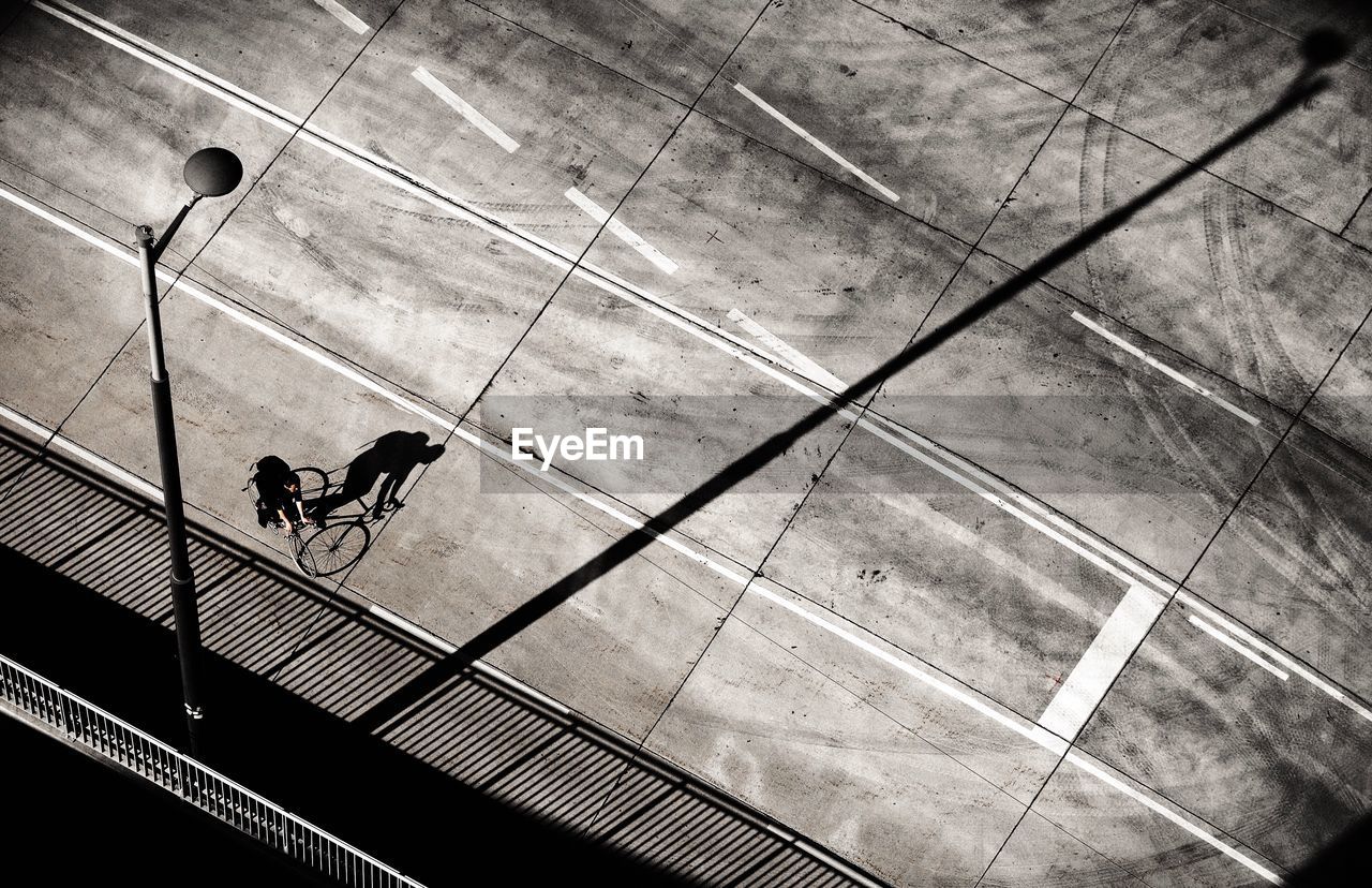 High angle view of man riding bicycle on street during sunny day