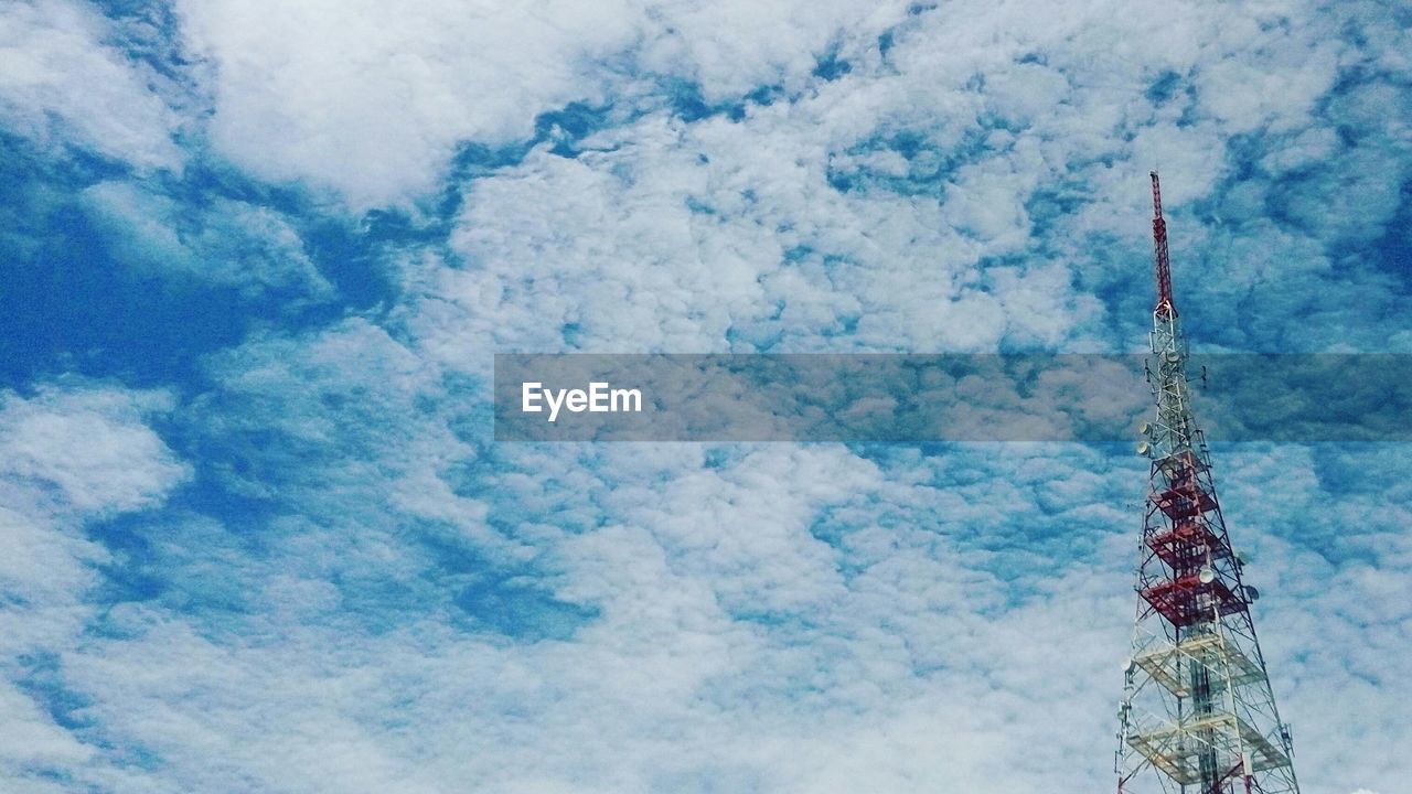 Low angle view of communications tower against cloudy sky