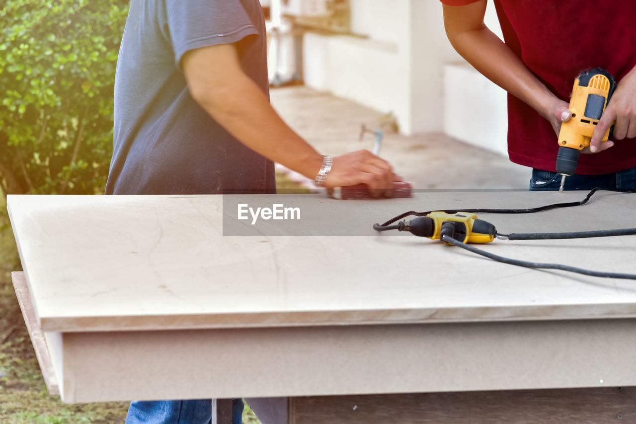 Cropped image of carpenters making furniture outdoors