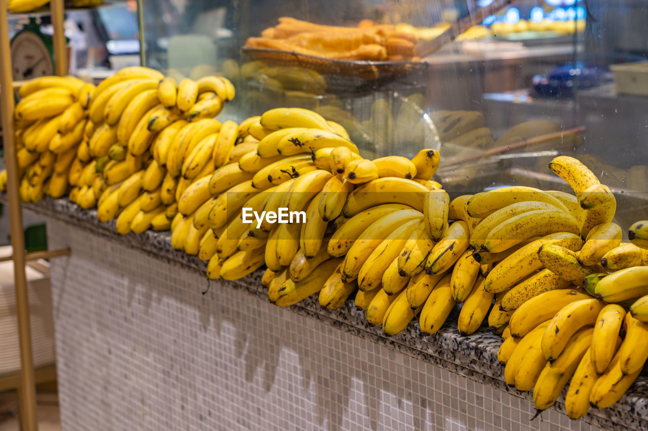 banana, food and drink, food, cooking plantain, freshness, healthy eating, business, yellow, fruit, produce, wellbeing, market, business finance and industry, retail, plant, abundance, market stall, no people, city, public space, large group of objects, occupation, tropical fruit, outdoors, ripe, store, street