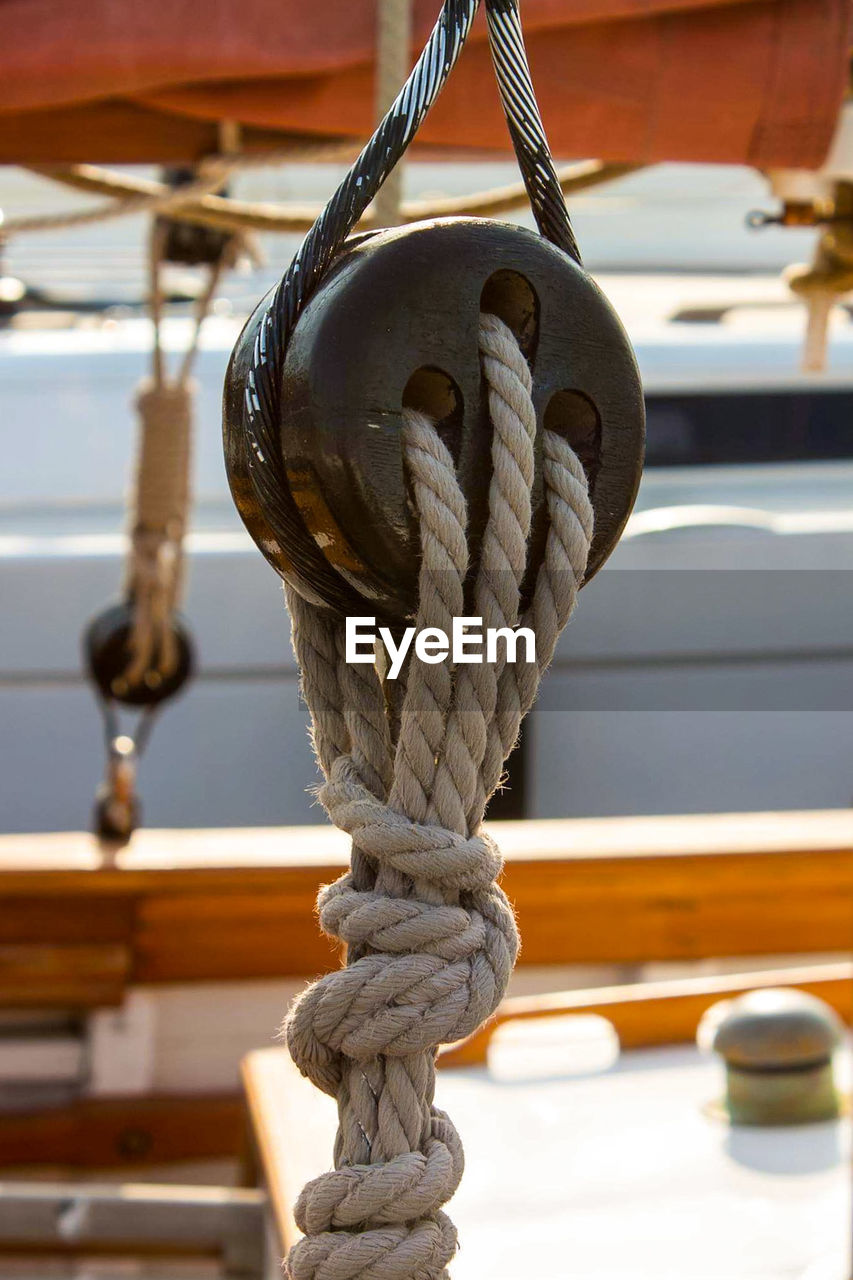 CLOSE-UP OF ROPE TIED TO BOLLARD ON BOAT