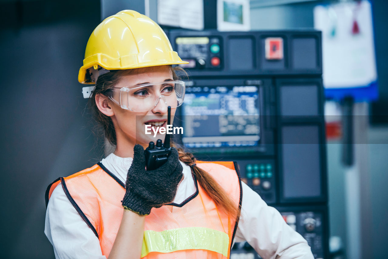 Young engineer talking on walkie talkie in factory