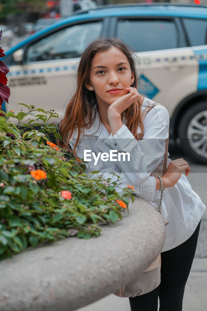 portrait of young woman sitting on car