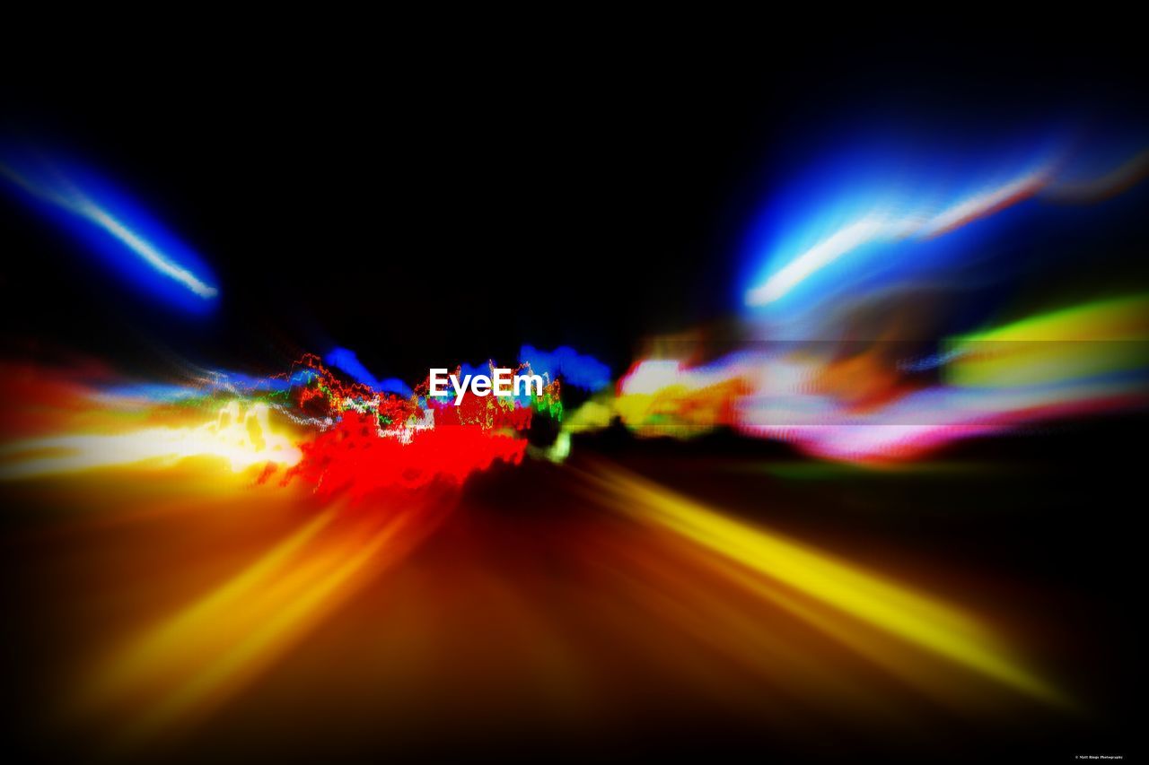 LIGHT TRAILS ON ILLUMINATED STREET AT NIGHT