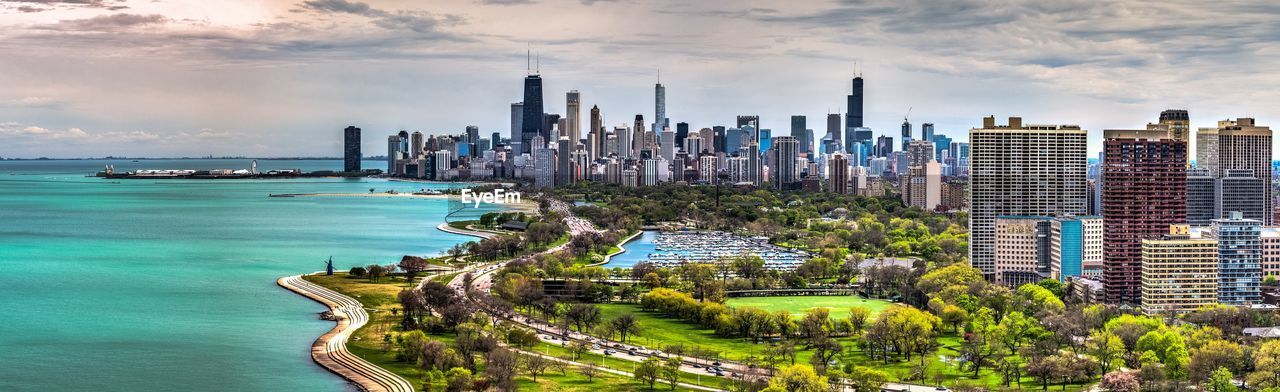 Panoramic view of buildings in city against cloudy sky