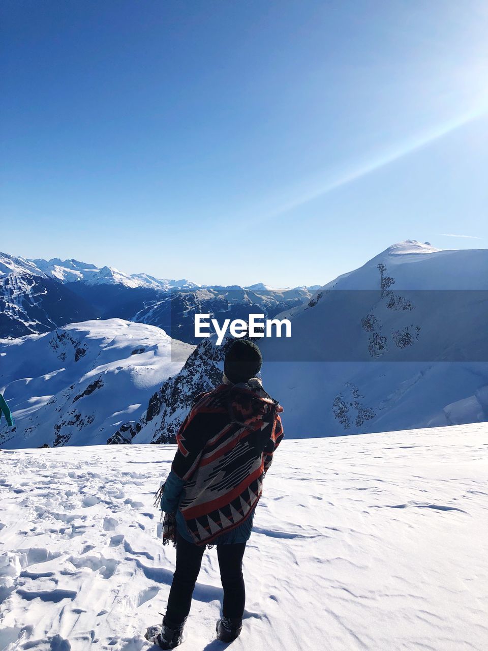 Rear view of woman on snowcapped mountain against sky