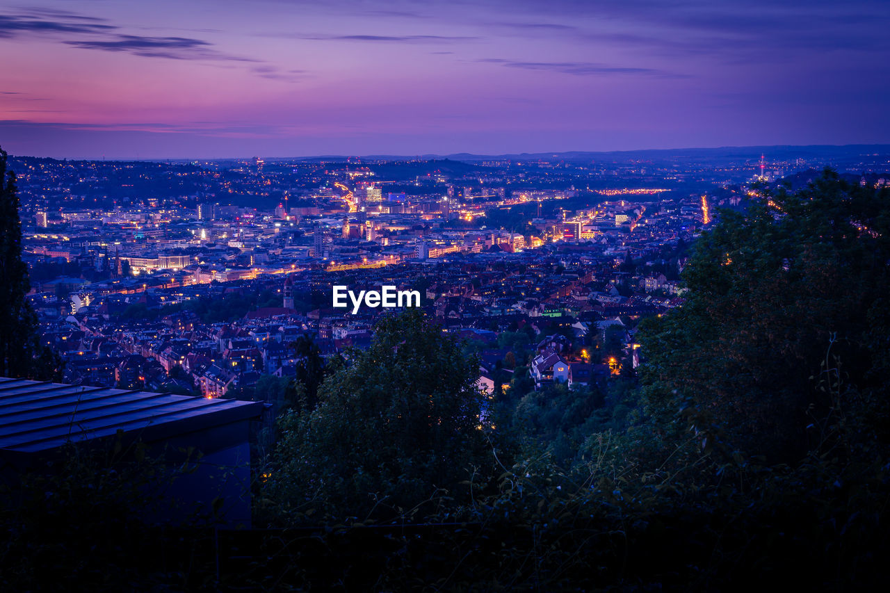 HIGH ANGLE VIEW OF ILLUMINATED CITY AT NIGHT