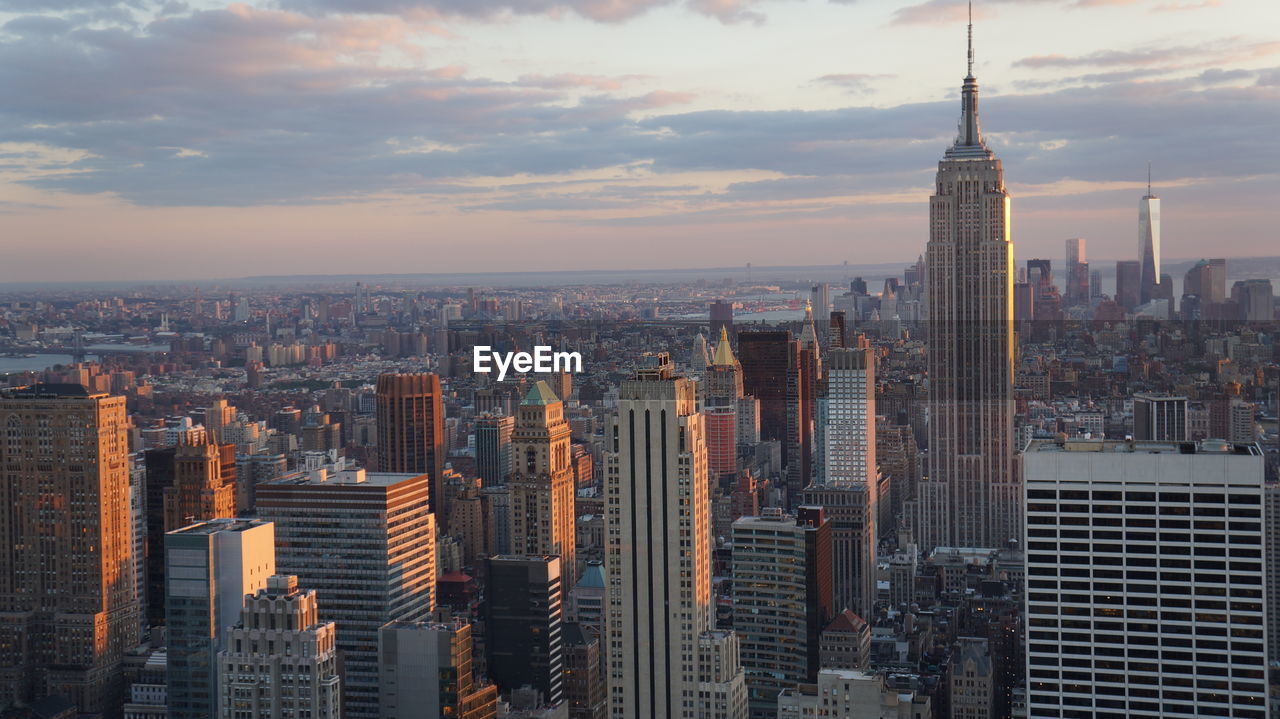 Aerial view of buildings in city against cloudy sky