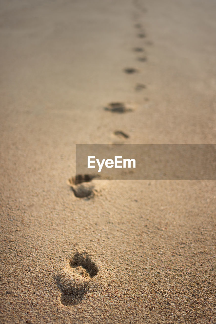 HIGH ANGLE VIEW OF FOOTPRINTS ON SANDY BEACH