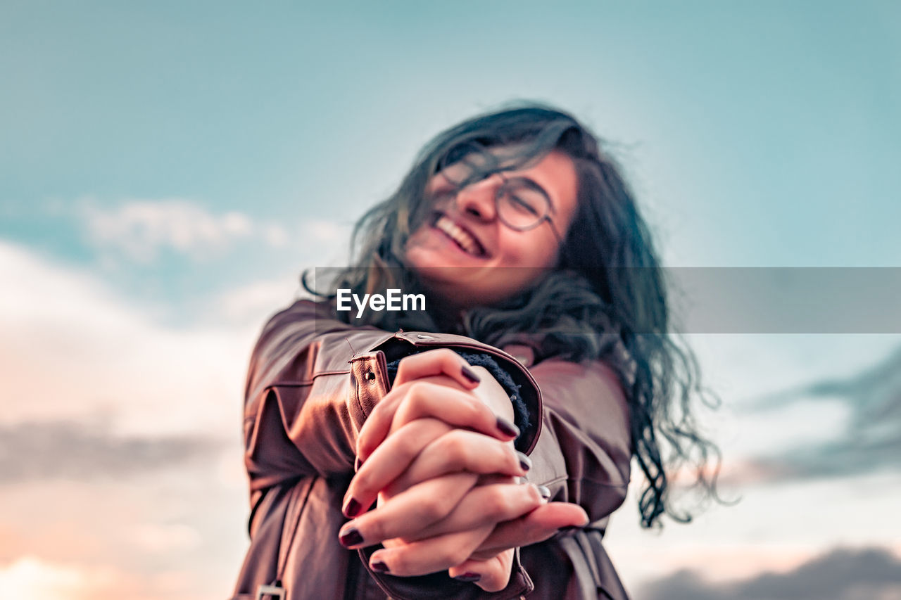 Cheerful young woman against sky