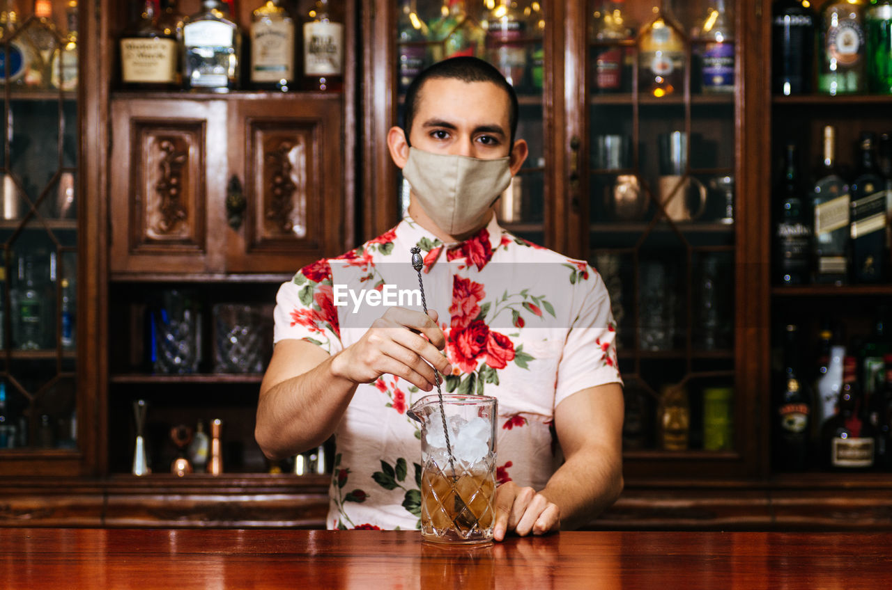 Portrait of man holding drink on bar counter