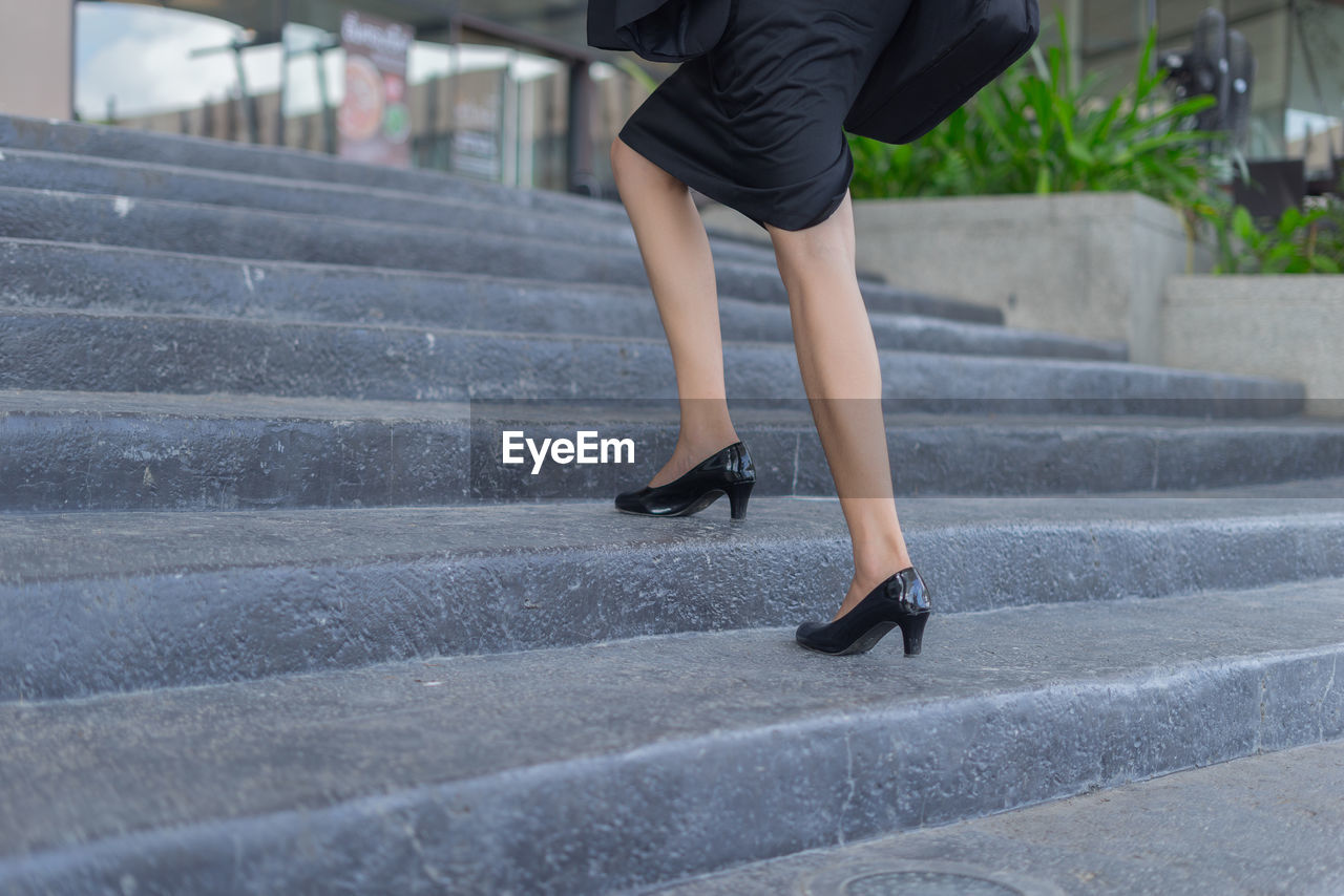 Low section of businesswoman walking on steps