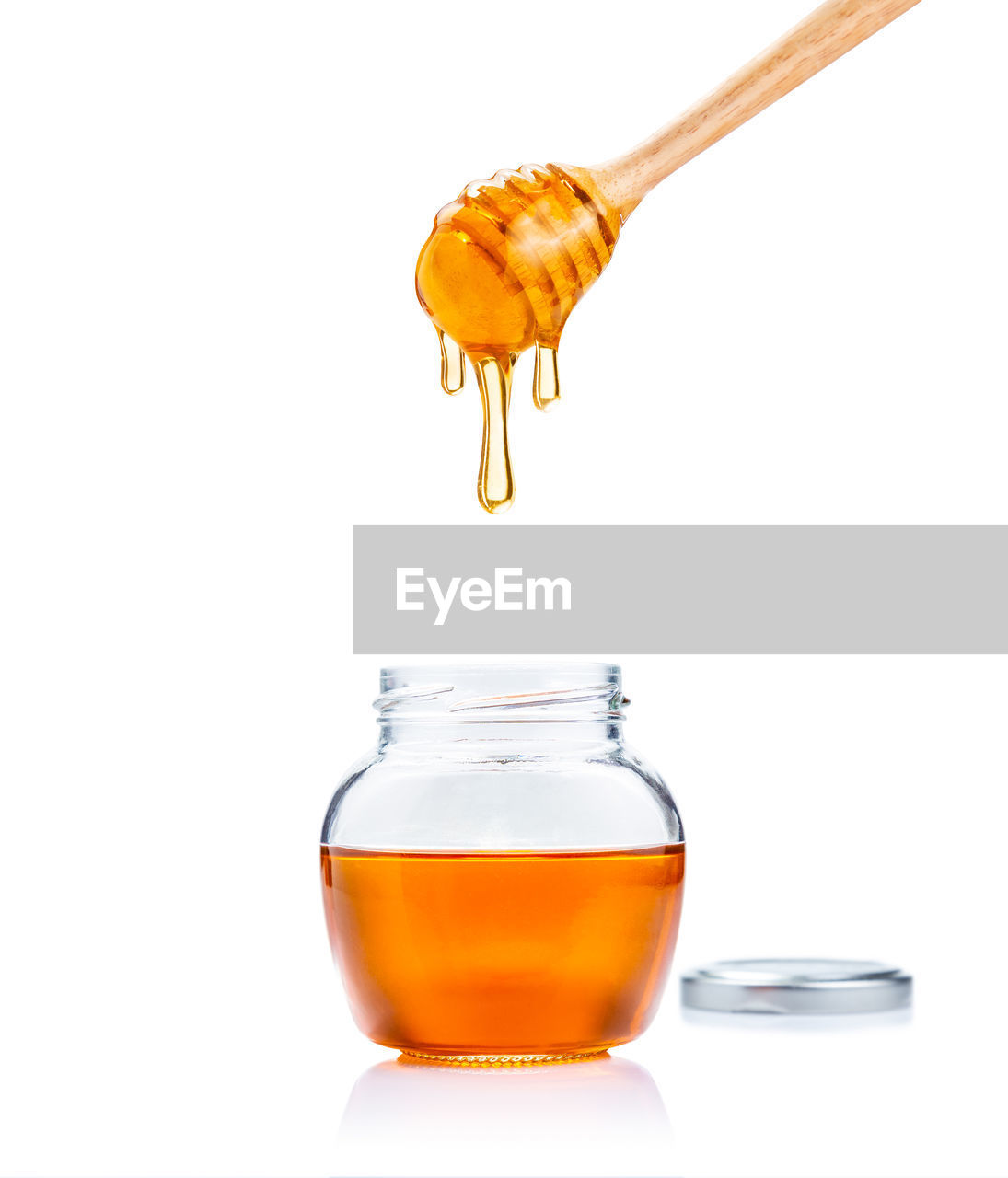 Honey in glass jar with wooden honey dipper