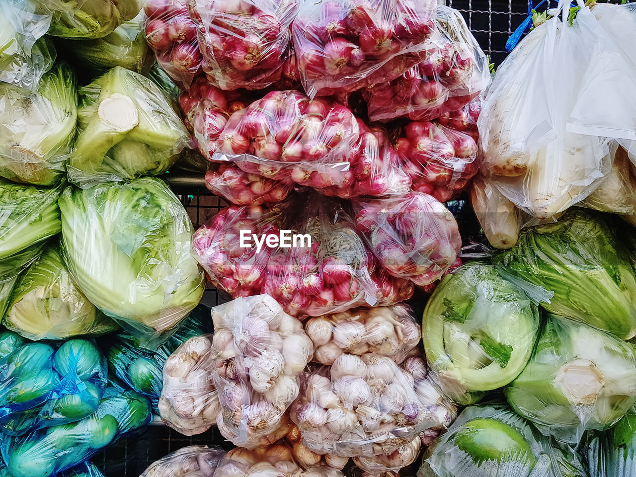 Various kinds of vegetables in plastic bags for sale at market stall