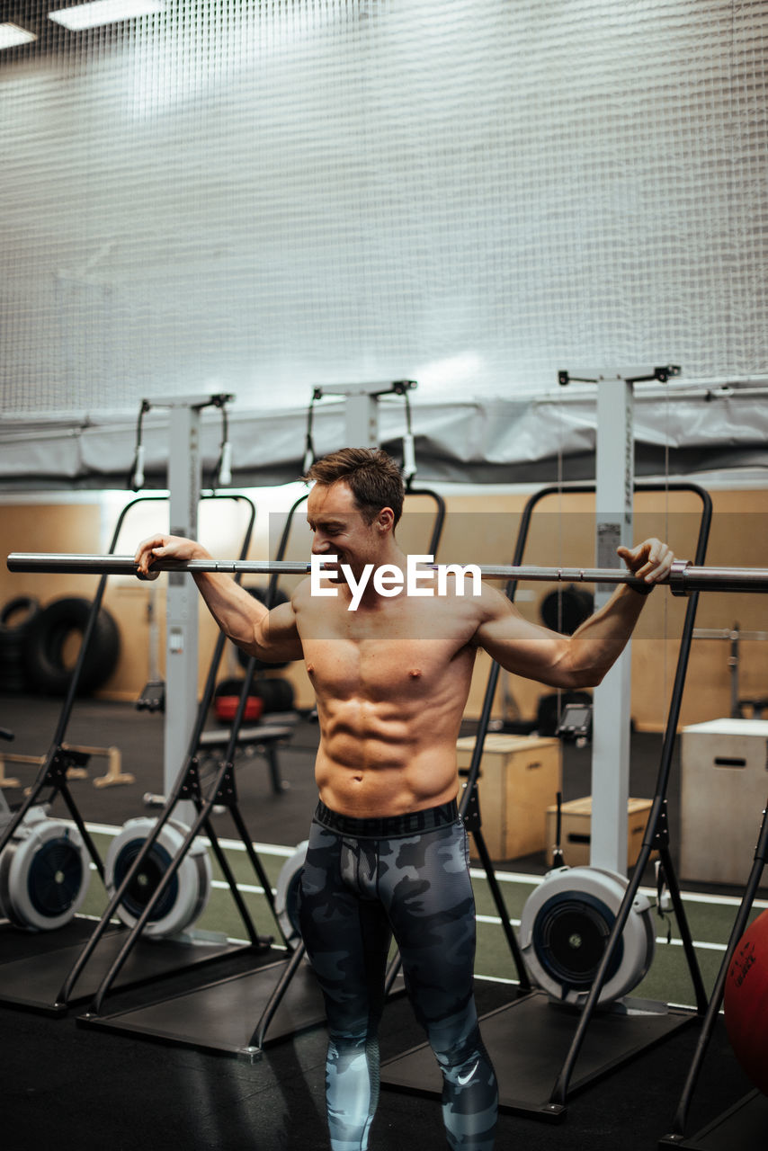 FULL LENGTH OF SHIRTLESS MAN SMOKING WHILE SITTING IN KITCHEN