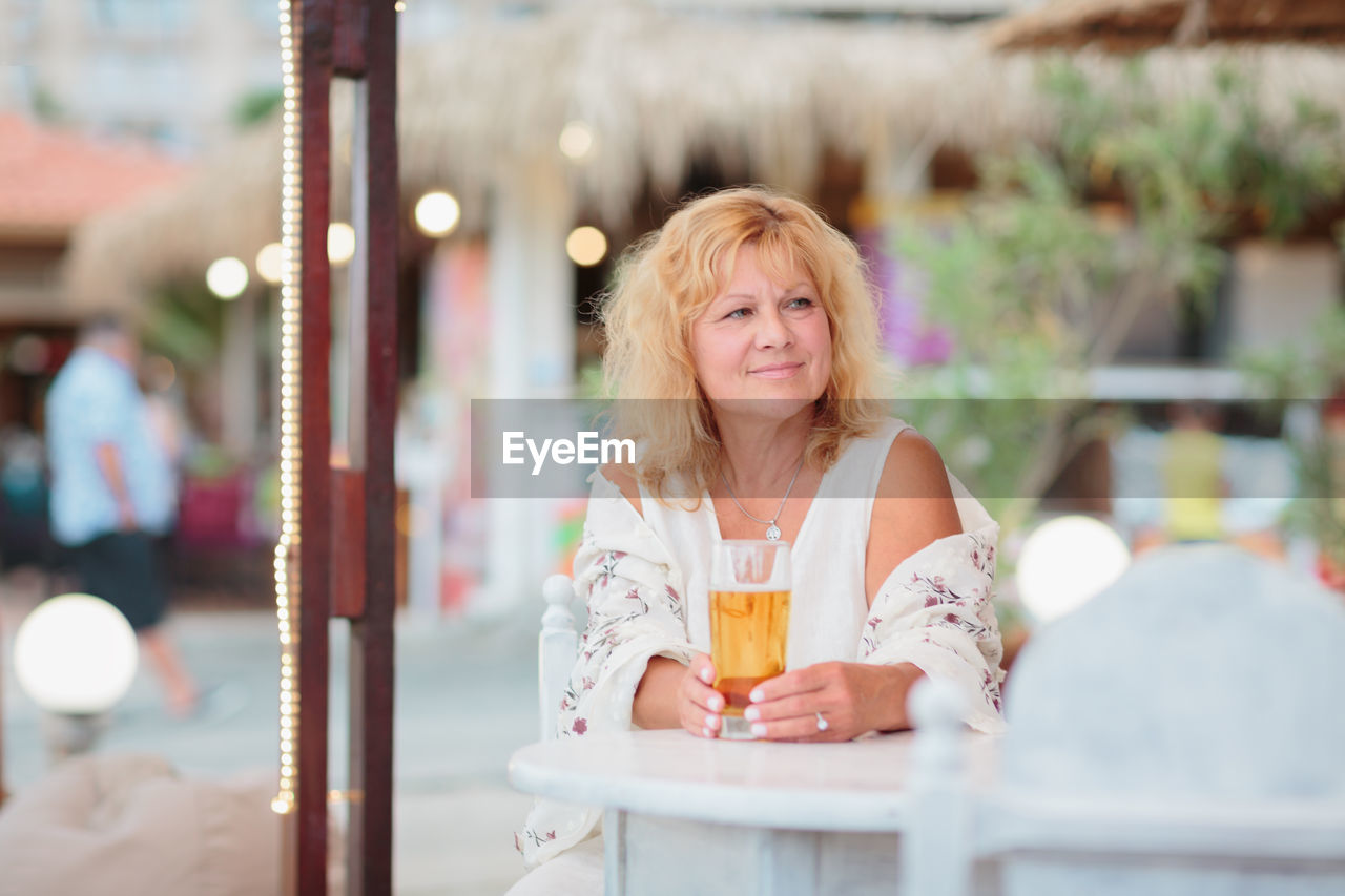 Portrait of woman drinking beer at beach cafe