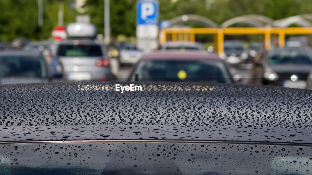 Rain drops on the black car roof sunny summer day
