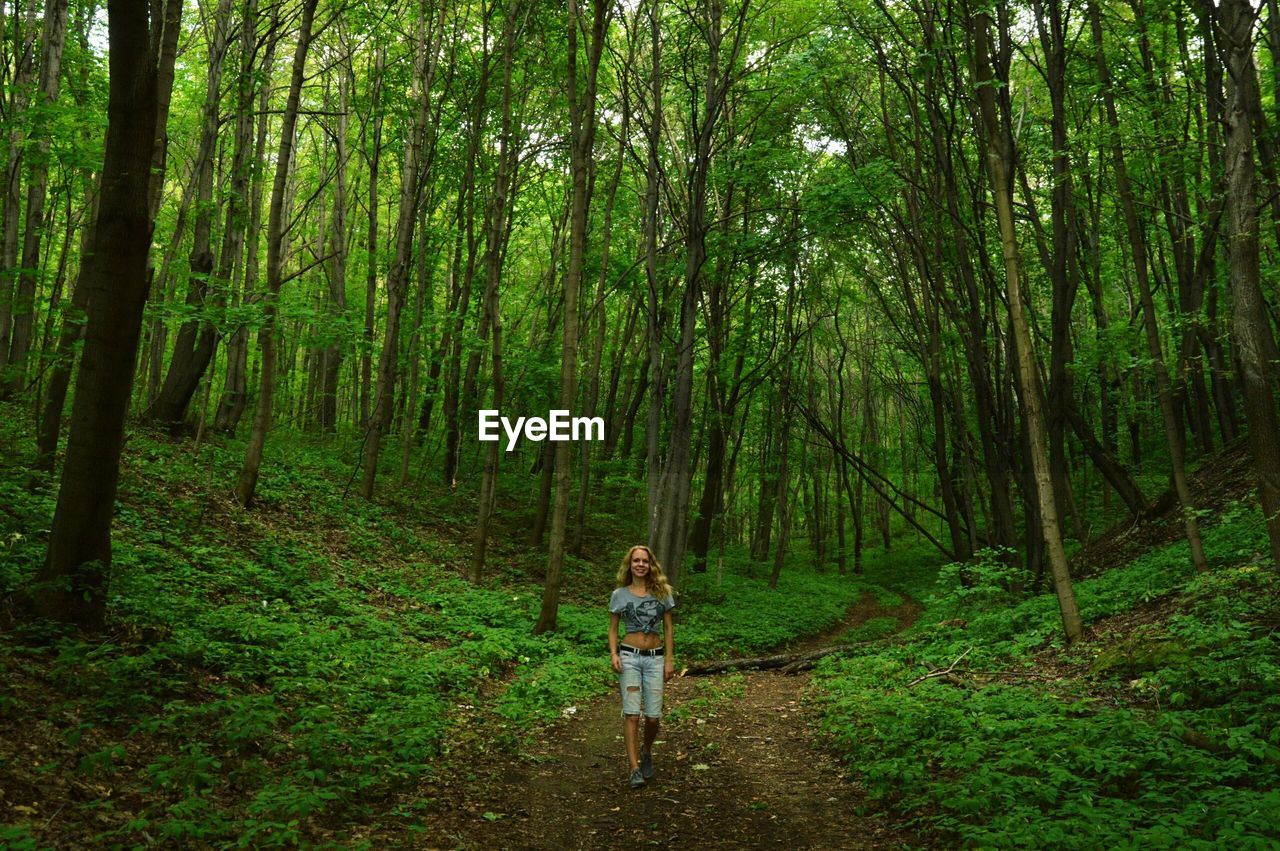 Full length of woman walking on field in forest