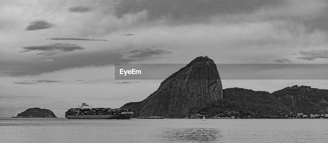 Photo of sugarloaf mountain with a cargo ship passing in front of it in guanabara bay