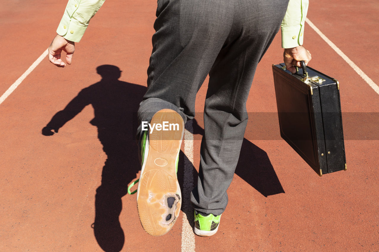 Low section of man running with briefcase on track