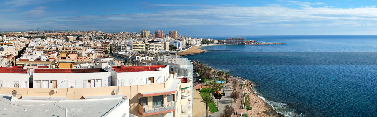 High angle view of town by sea against sky