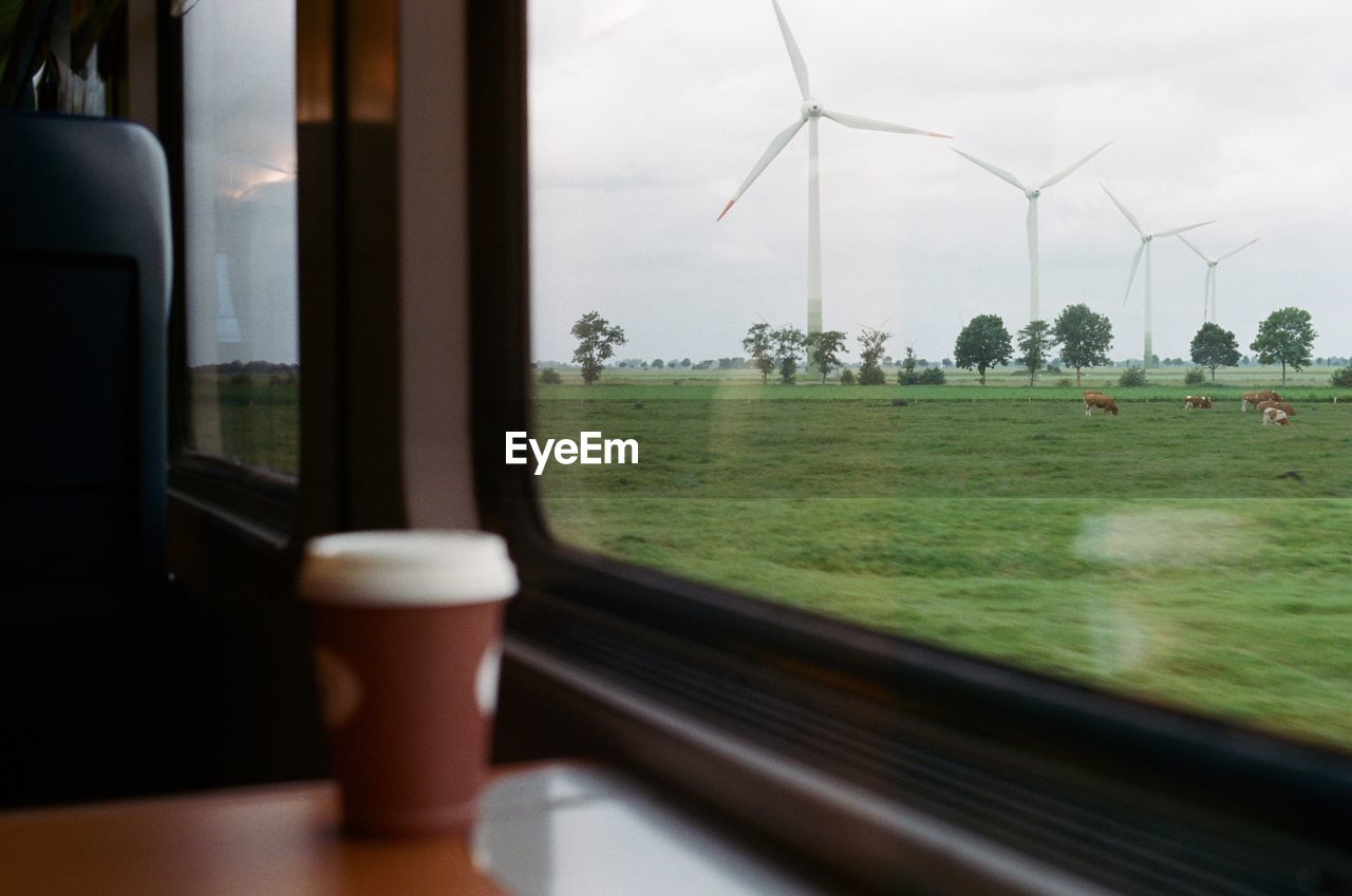 Windmills on field seen through train window