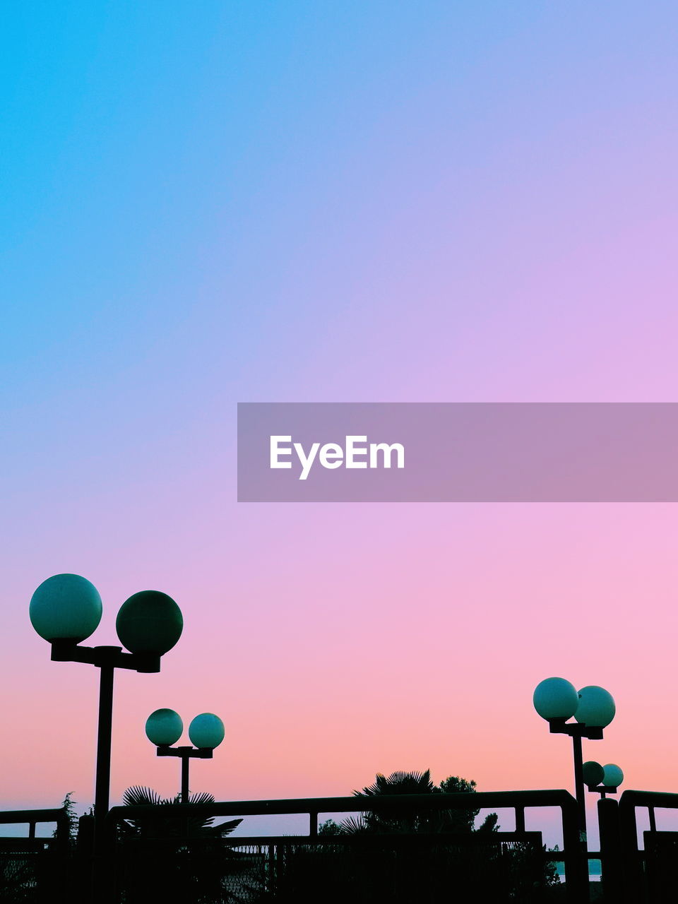 LOW ANGLE VIEW OF STREET LIGHTS AGAINST SKY AT SUNSET