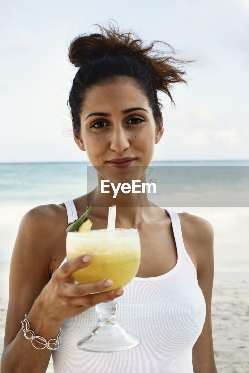 Smiling young with cocktail on beach