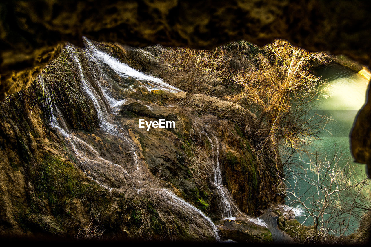 CLOSE-UP OF WATER FLOWING THROUGH ROCKS