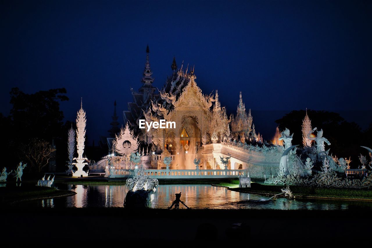 Illuminated temple building against sky at night