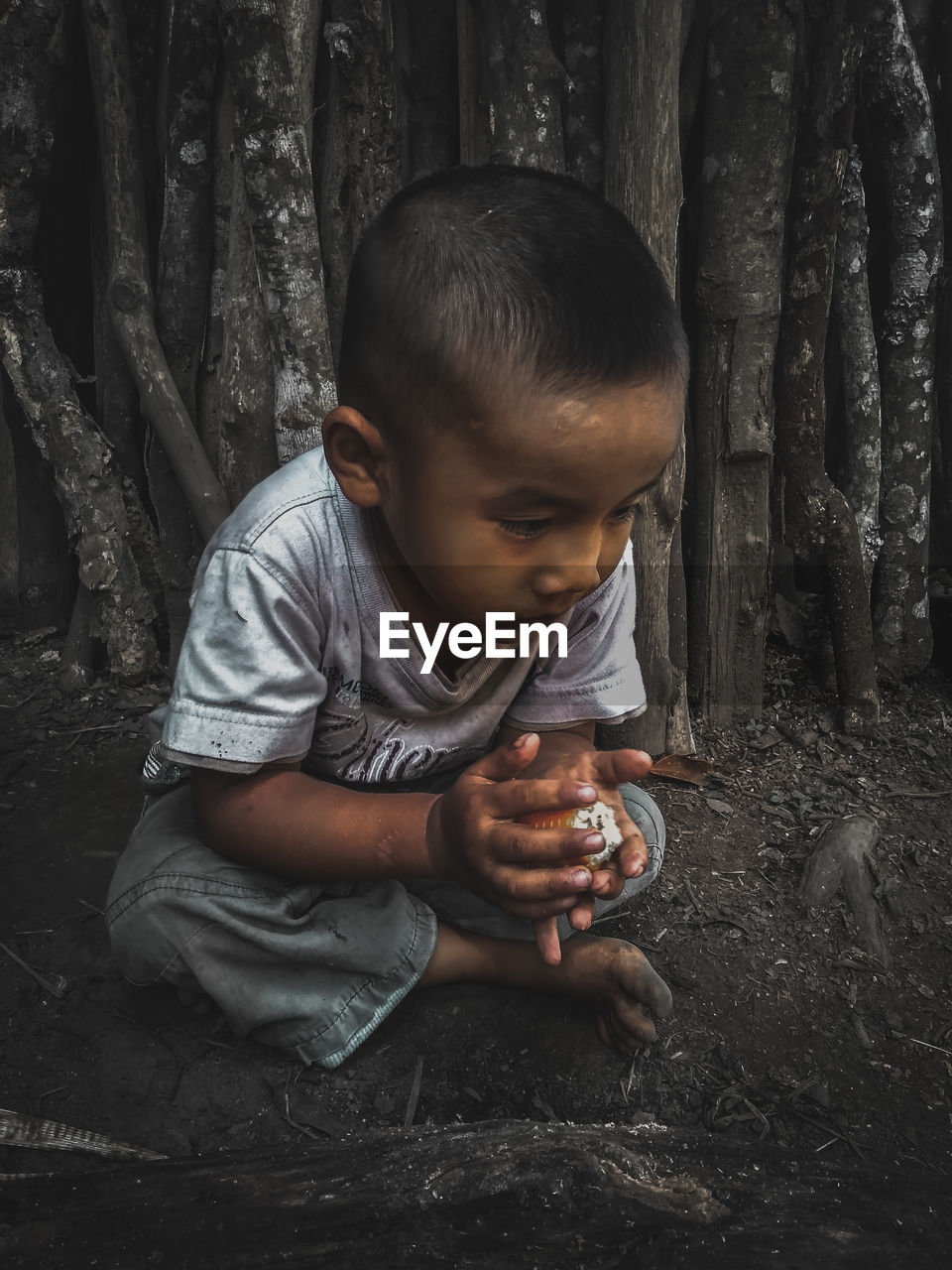 Cute boy looking away while sitting on land