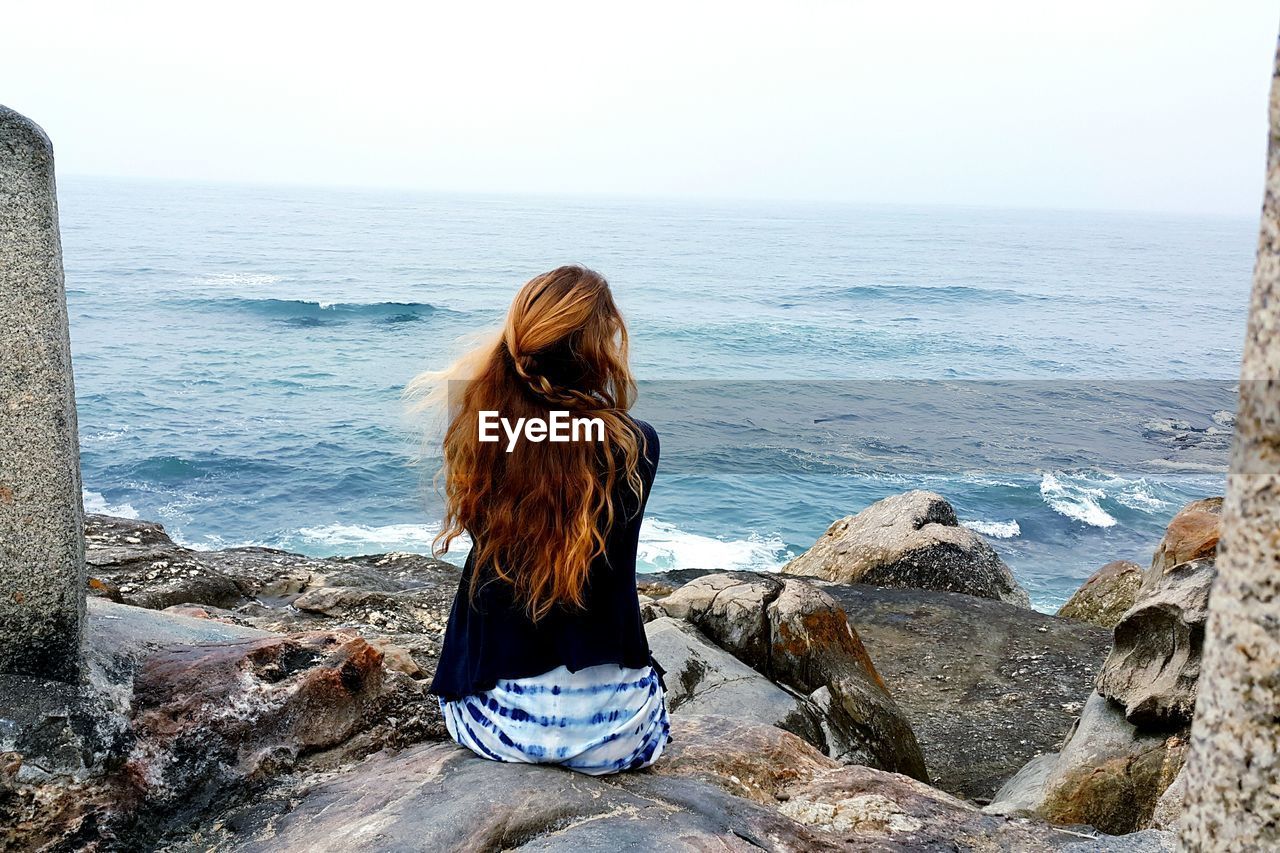 Rear view of woman overlooking calm sea