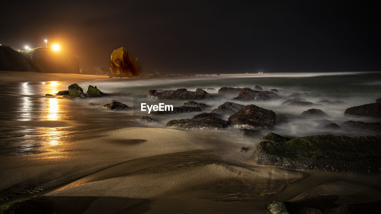 SCENIC VIEW OF BEACH AGAINST SKY AT SUNSET