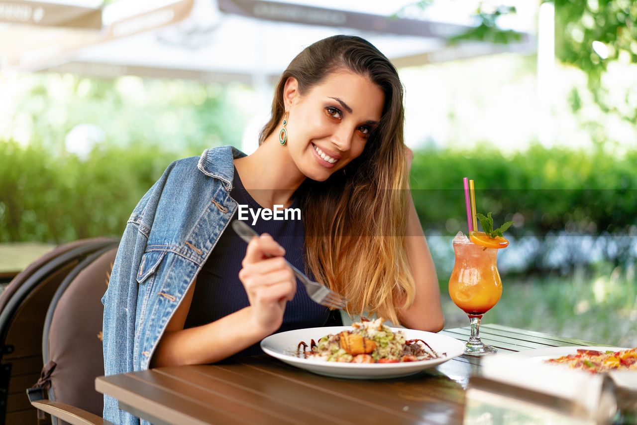 Portrait of smiling young woman sitting at restaurant table