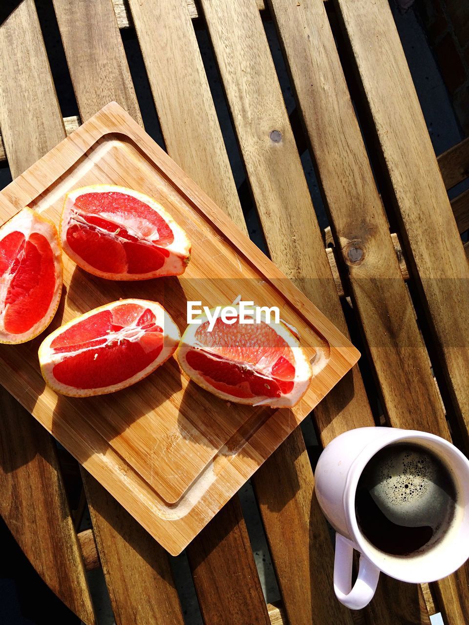 High angle view of sliced grapefruits on wooden tray with black coffee